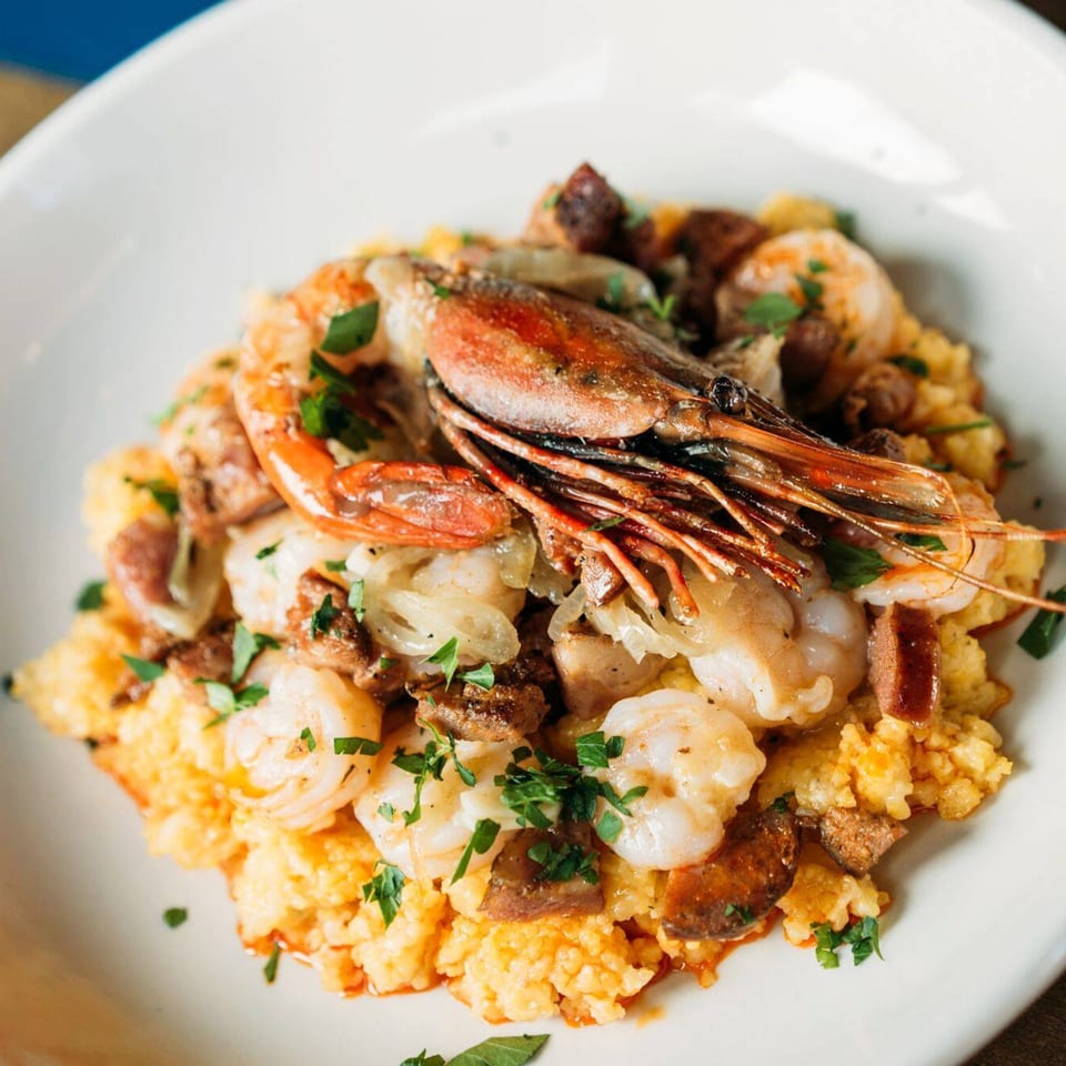 Shrimp and grits with sausage and parsley in a white bowl at The Cavalier.