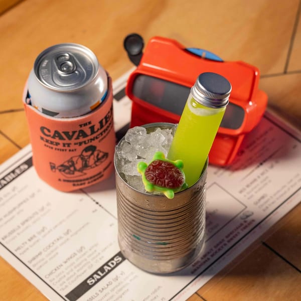 A Cavalier koozie, a cocktail in a tin can with a gummy turtle, and a View-Master.